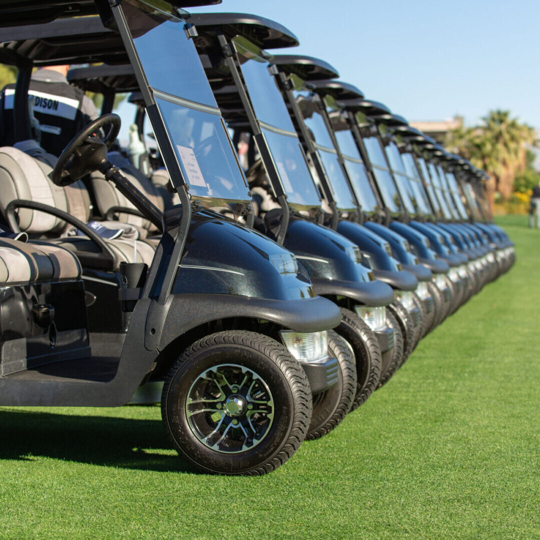 A row of golf carts parked on the grass.